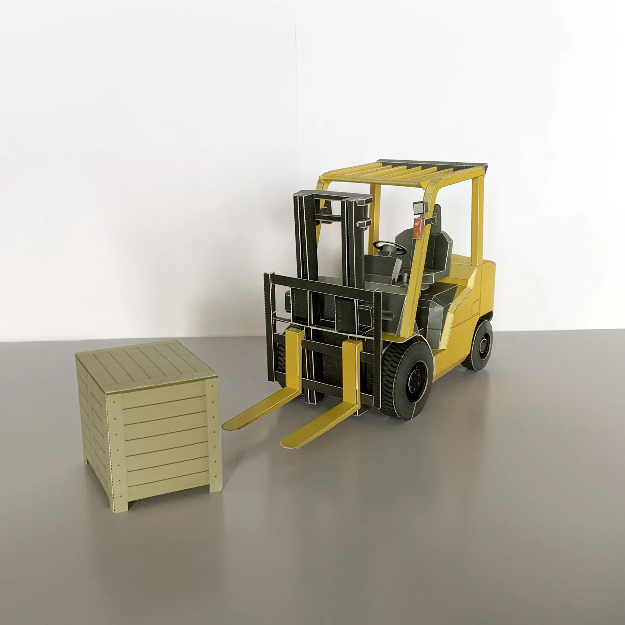 フォークリフトの模型と木製パレットを並べて撮影。運転席やマストの構造まで再現したペーパークラフト