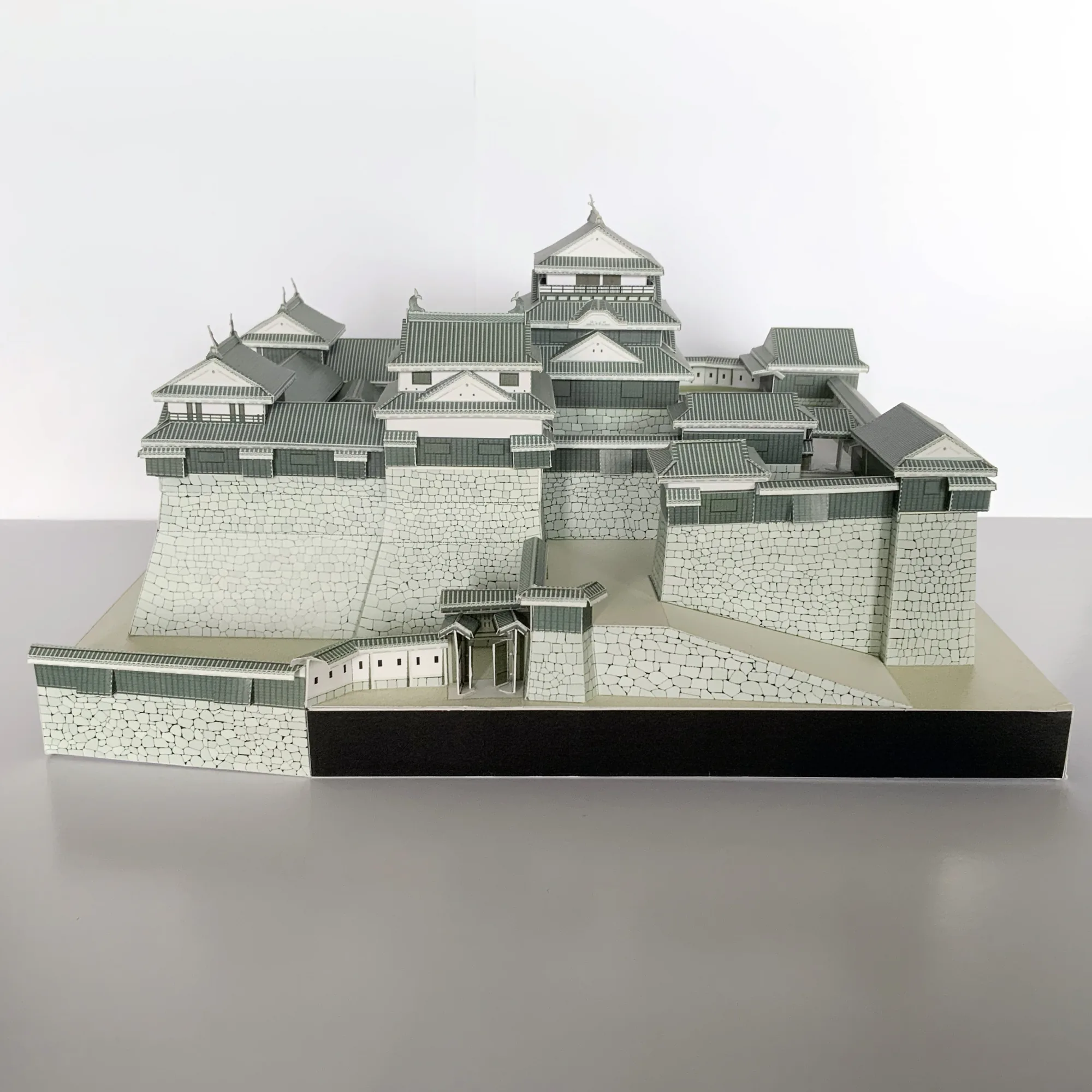 松山城のペーパークラフト建築模型を正面から見た全景。連立式天守と石垣を白一色で構成した城郭模型