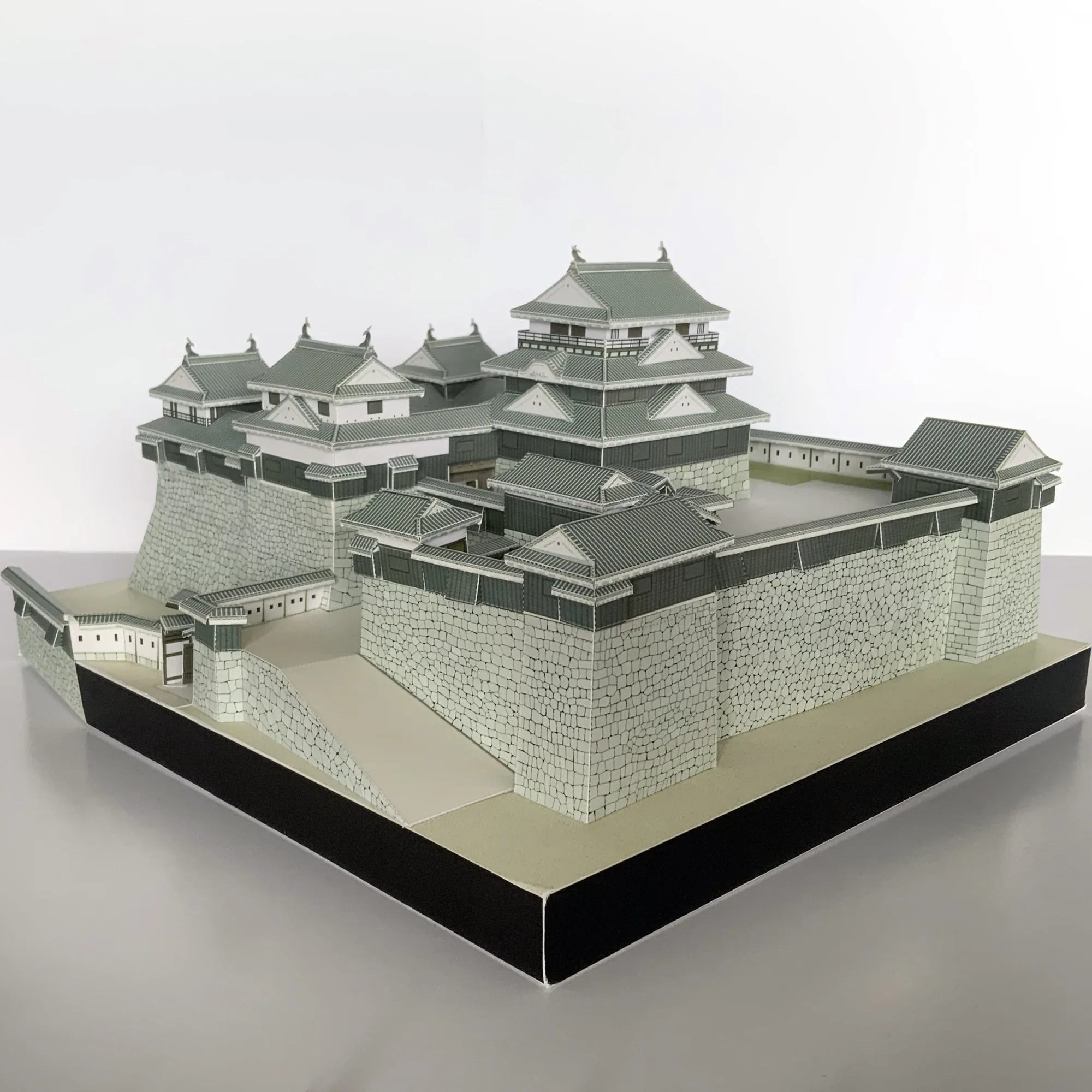 松山城の建築模型を斜め上から撮影。天守群と櫓、勾配のある石垣を紙で立体化した城郭模型