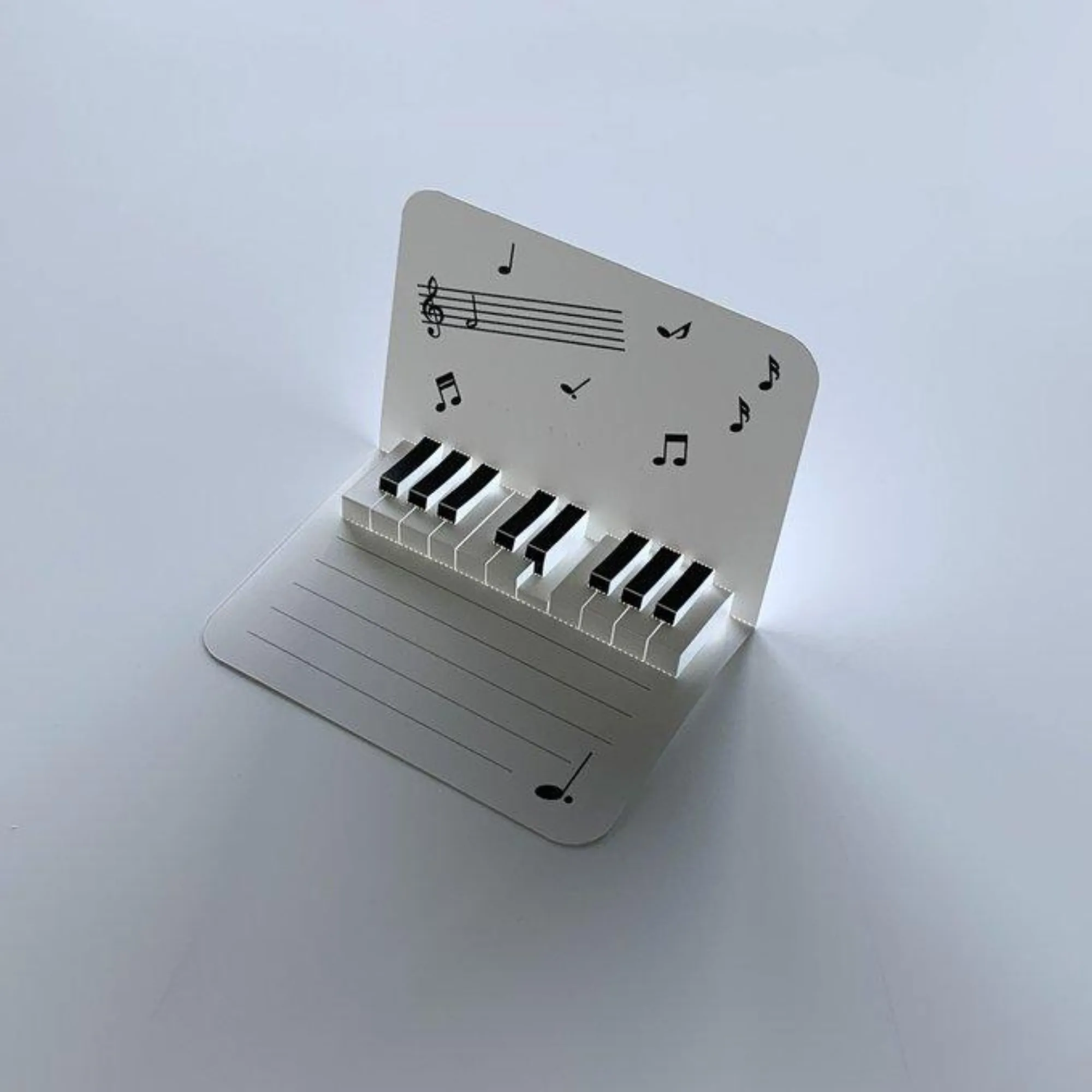 ピアノの鍵盤と音符をあしらった立体ポストカード。黒鍵と白鍵を立ち上げた音楽モチーフのペーパークラフト